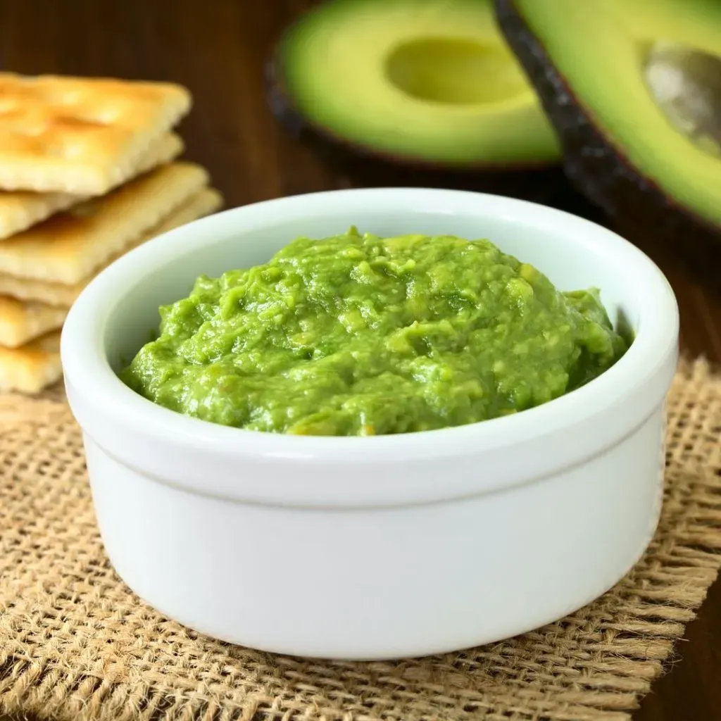 Crema de palta en un pequeño recipiente blanco de vidrio.