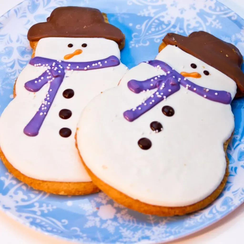 Galleta de muñecos de nieva decoradas con un glaseado blanco, café, morado y naranjo.