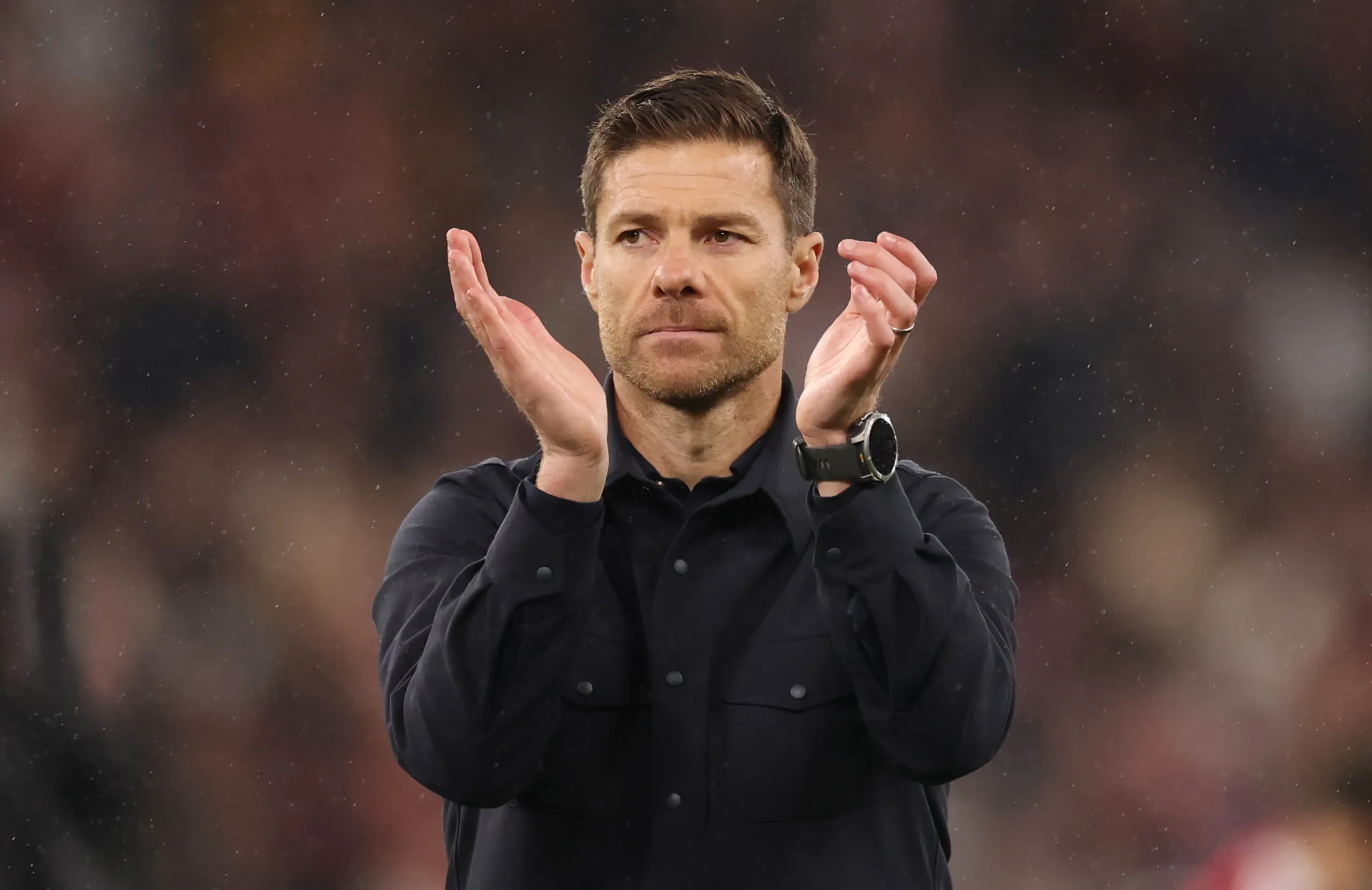 Xabi Alonso veste roupa preta e faz gesto de aplauso