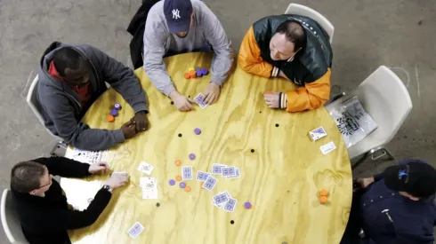 Amigos jogando poker em uma mesa redonda (Foto: Getty images)
