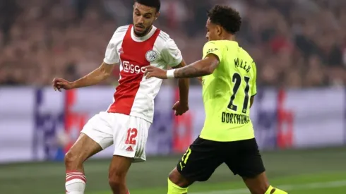 Noussair Mazraoui of Ajax (left) tries to pass the ball infront to avoid Donyell Malen of Borussia
