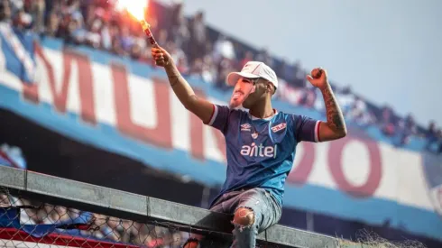 A fan with a flare wears a mask of Luis Suarez during the unveiling of the Uruguayan player Luis Suarez as the new player of Nacional at the Parque Central Stadium on July 31, 2022 in Montevideo, Uruguay.