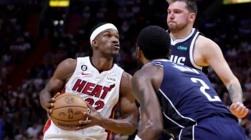 Jimmy Butler #22 of the Miami Heat drives against Kyrie Irving #2 and Luka Doncic #77 of the Dallas Mavericks
