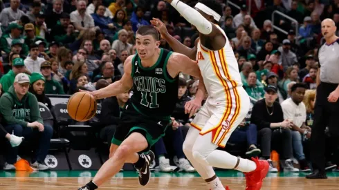 Payton Pritchard #11 of the Boston Celtics dribbles the ball around Aaron Holiday #3 of the Atlanta Hawks
