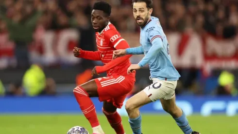 Alphonso Davies of FC Bayern Munich battles for possession with Bernardo Silva of Manchester City