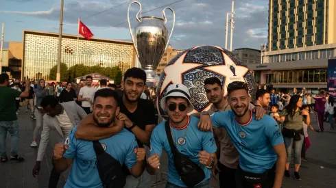 Fans of Manchester City pose in front of a giant replica of the Champions League trophy in Taksim Square ahead of the 2022-2023 UEFA Champions League final