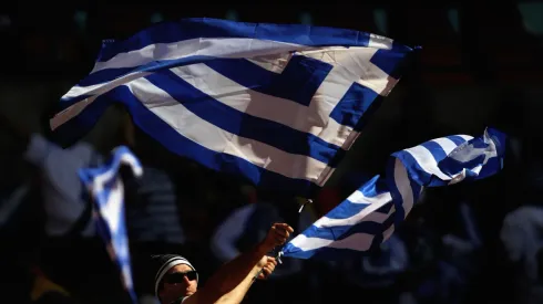 A Greece fan waves flags
