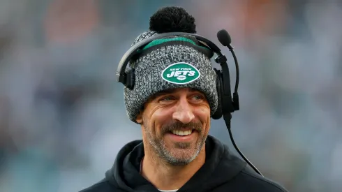 Aaron Rodgers smiling on the sidelines during a New York Jets' game.
