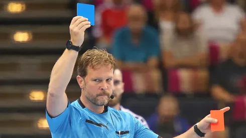 Referee Martin Thoene with blue card during a handball match
