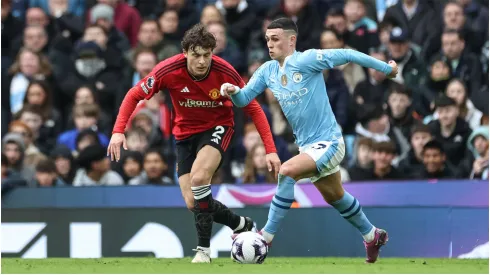 Phil Foden of Manchester City breaks with the ball tracked by Victor Lindelöf of Manchester United
