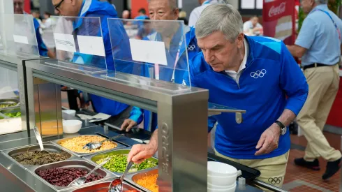 IOC President Thomas Bach tries food from a salad bar while touring the Olympic Village ahead of the start of the Paris 2024 Olympic Games on July 22, 2024 in Paris, France.
