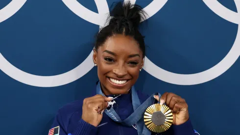 Gold medalist Simone Biles of Team United States poses with the Olympic Rings and a goat charm on her necklace during the Artistic Gymnastics Women's All-Around Final.
