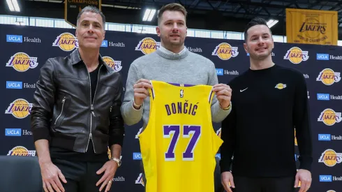 Luka Doncic (C) of the Los Angeles Lakers holds his new jersey while standing alongside general manager Rob Pelinka (L) and head coach JJ Redick.