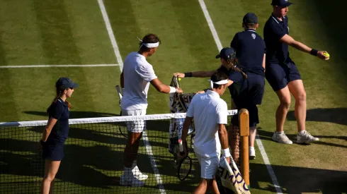 A ball kid passes a towel to Rafael Nadal as he and Roger Federer of Switzerland walk back to their chairs before a change of serve in their Men's Singles semi-final match against Roger Federer in 2019.