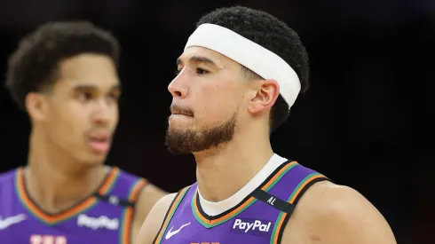 Devin Booker #1 of the Phoenix Suns and Oso Ighodaro #4 during the second half of the NBA game at PHX Arena on March 14, 2025 in Phoenix, Arizona.