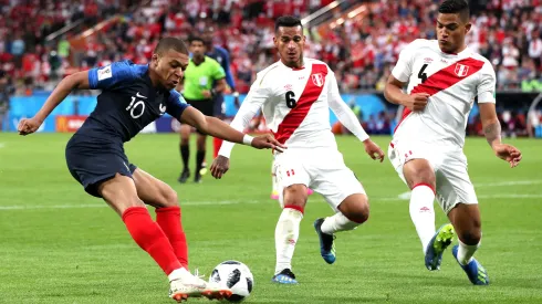 YEKATERINBURG, RUSSIA – JUNE 21:  Kylian Mbappe of France crosses the ball under pressure from Miguel Trauco of Peru and Anderson Santamaria of Peru  during the 2018 FIFA World Cup Russia group C match between France and Peru at Ekaterinburg Arena on June 21, 2018 in Yekaterinburg, Russia.  (Photo by Kevin C. Cox/Getty Images)
