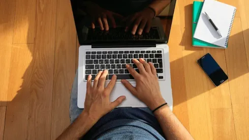 Workspace at home. Student working with a laptop on the floor.
