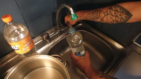 Persona juntando agua durante un corte de agua.
