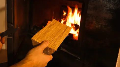 Hombre poniendo leña en una chimenea.
