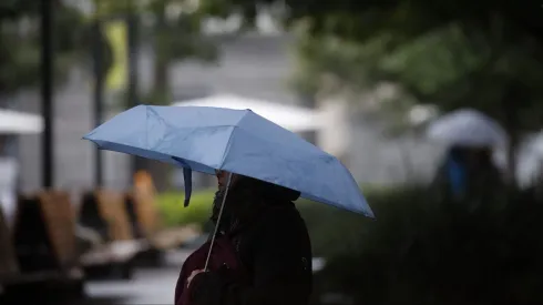Transeuntes circulan por la Plaza de armas bajo la Lluvia en Santiago.
