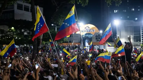 Personas levantan banderas durante el acto de cierre de campaña electoral del candidato presidencial opositor Edmundo González. 25 de julio de 2024 en Caracas, Venezuela. 
