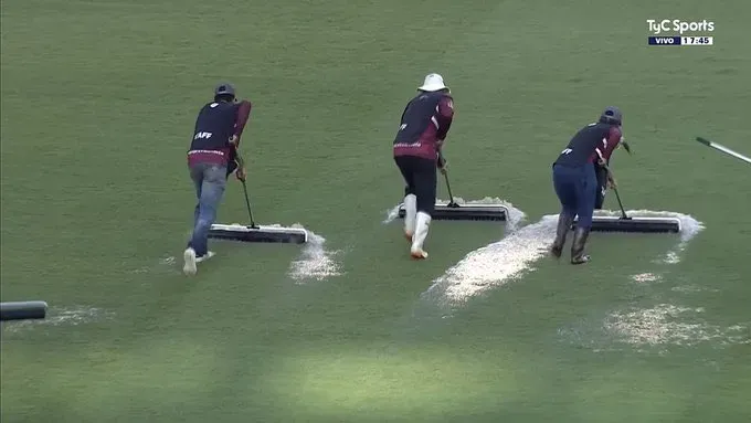 Colaboradores de la organización local salieron al campo de juego con rodillos para tratar de sacar el agua hacia afuera.