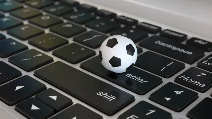 Imagem parcial de teclado de computador, com uma pequena bola de futebol sobre a tecla Enter