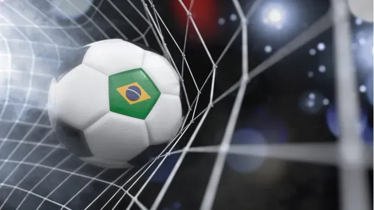 Bola de futebol com representação da bandeira do Brasil está contra a rede da baliza