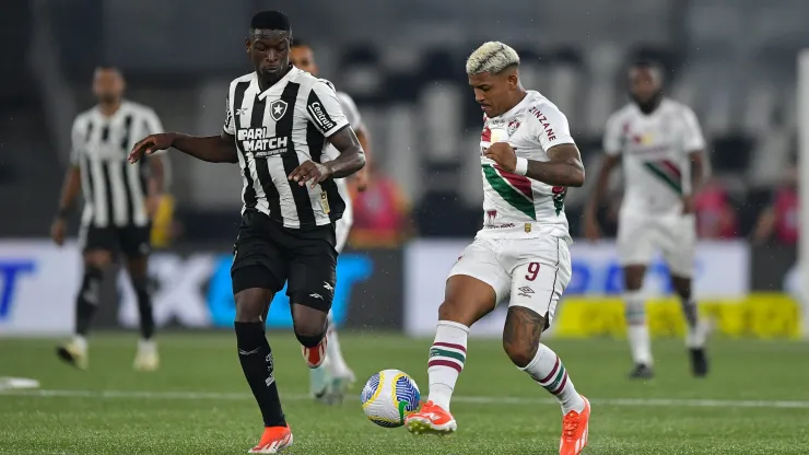 Jogador do Botafogo disputa lance com jogador do Fluminense durante partida. Foto: Thiago Ribeiro/AGIF
