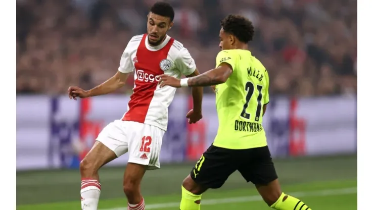 Noussair Mazraoui of Ajax (left) tries to pass the ball infront to avoid Donyell Malen of Borussia
