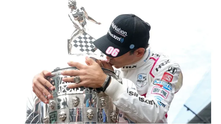 Helio Castroneves kisses the winner's trophy
