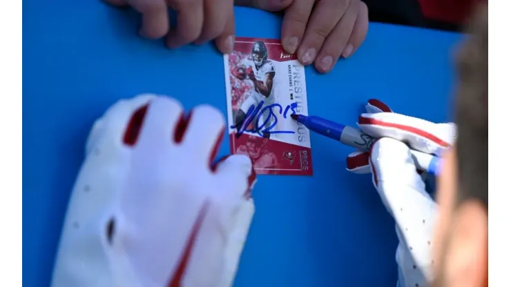 Mike Evans #13 of the Tampa Bay Buccaneers signs a card for a fan during pregame against the Carolina Panthers at Bank of America Stadium on October 23, 2022 in Charlotte, North Carolina.
