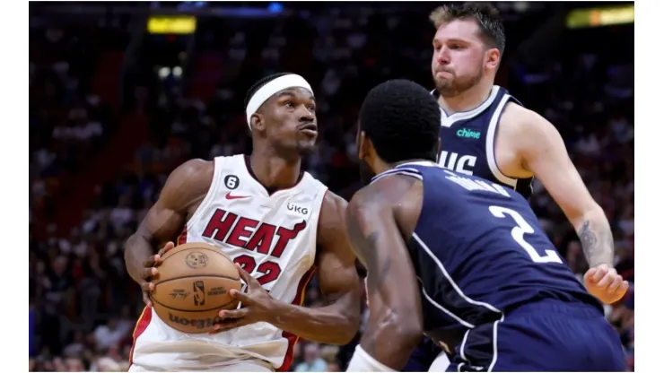 Jimmy Butler #22 of the Miami Heat drives against Kyrie Irving #2 and Luka Doncic #77 of the Dallas Mavericks
