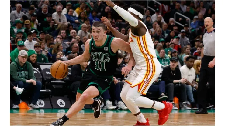 Payton Pritchard #11 of the Boston Celtics dribbles the ball around Aaron Holiday #3 of the Atlanta Hawks
