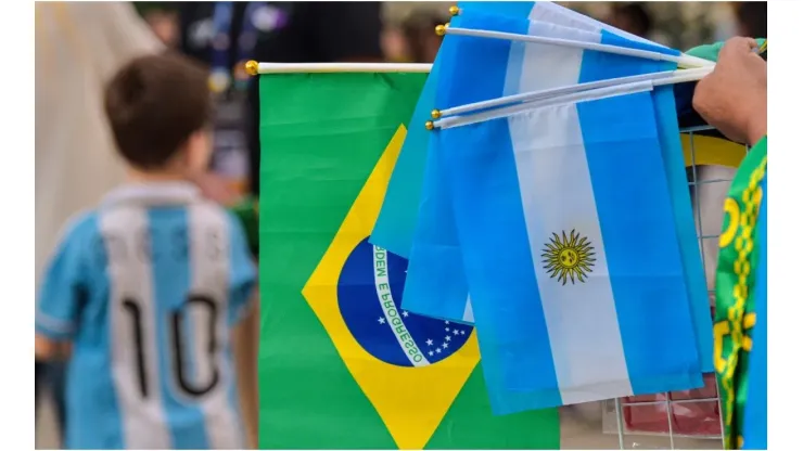 A street vendor holds flags of Argentina and Brazil outside the stadium
