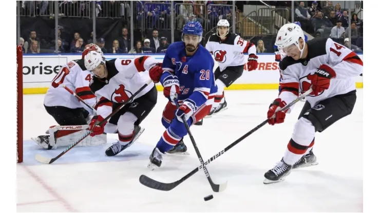 Chris Kreider #20 of the New York Rangers and Nathan Bastian #14 of the New Jersey Devils battle for the puck
