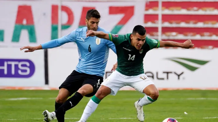 Moises Villarroel of Bolivia fights for the ball with Rodrigo Bentancur of Uruguay.
