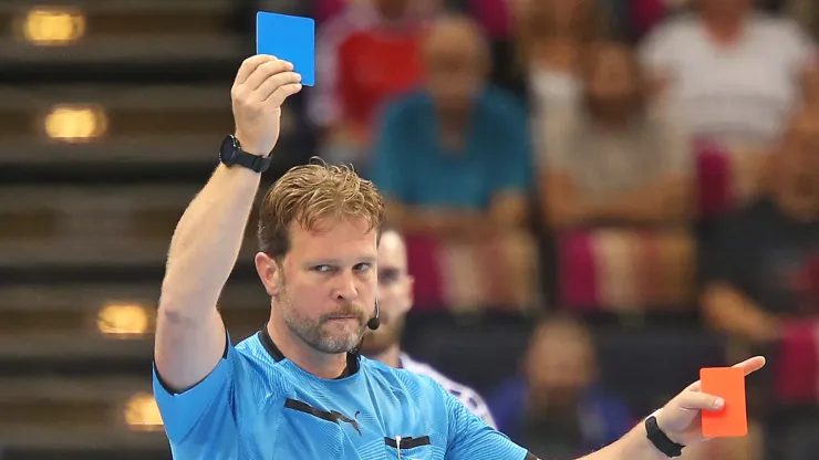 Referee Martin Thoene with blue card during a handball match
