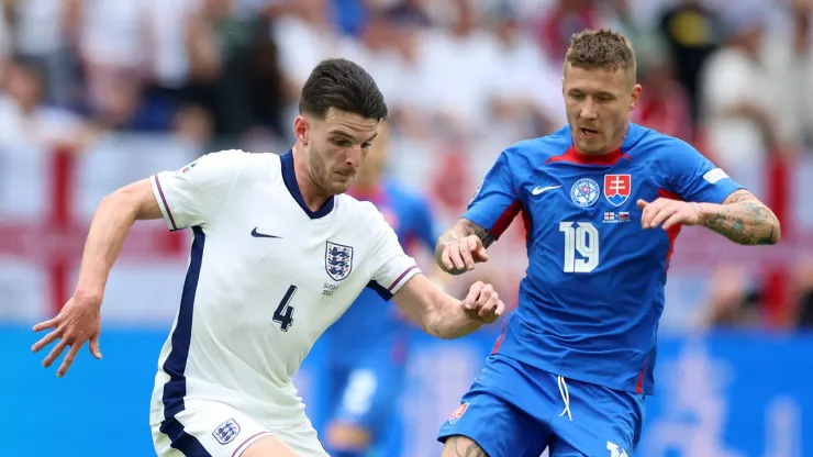 Declan Rice of England runs with the ball under pressure from Juraj Kucka of Slovakia during the UEFA EURO 2024 round of 16 match between England and Slovakia at Arena AufSchalke on June 30, 2024 in Gelsenkirchen, Germany.
