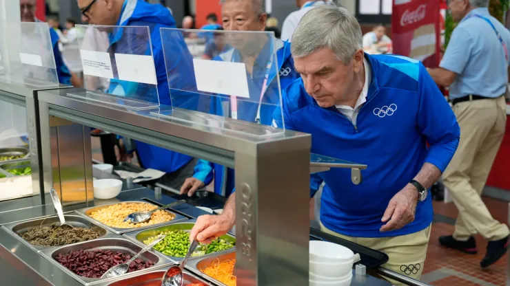 IOC President Thomas Bach tries food from a salad bar while touring the Olympic Village ahead of the start of the Paris 2024 Olympic Games on July 22, 2024 in Paris, France.
