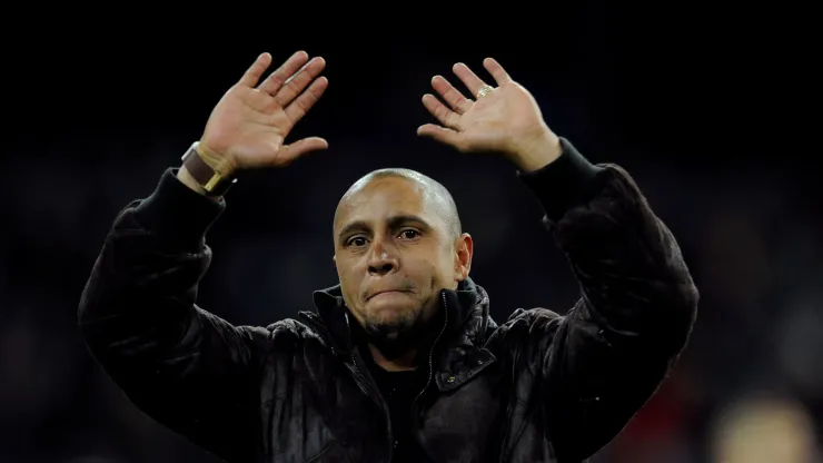 Former Real Madrid player Roberto Carlos waves to supporters after he was presented with a trophy for his achievements at the club
