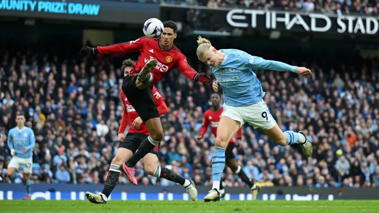 Erling Haaland y Raphaël Varane disputan el balón en el último clásico de Manchester.
