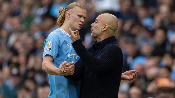 Erling Haaland conversa com Pep Guardiola no Manchester City.
