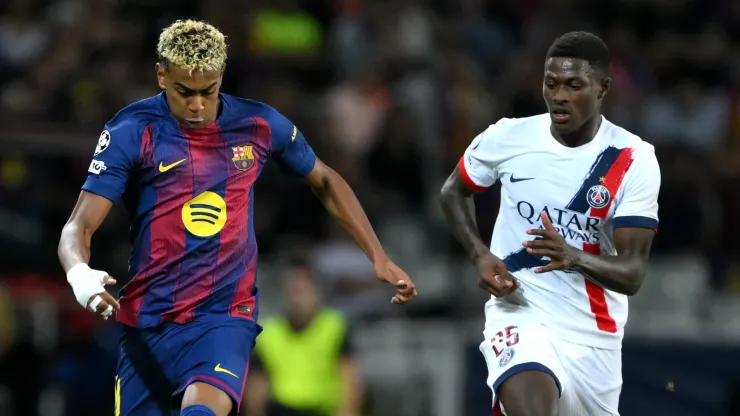 Lamine Yamal of FC Barcelona runs with the ball whilst under pressure from Nuno Mendes of Paris Saint-Germain.
