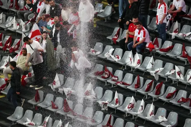 Los fanáticos intentando escapar de la zona donde cae el agua dentro del estadio.