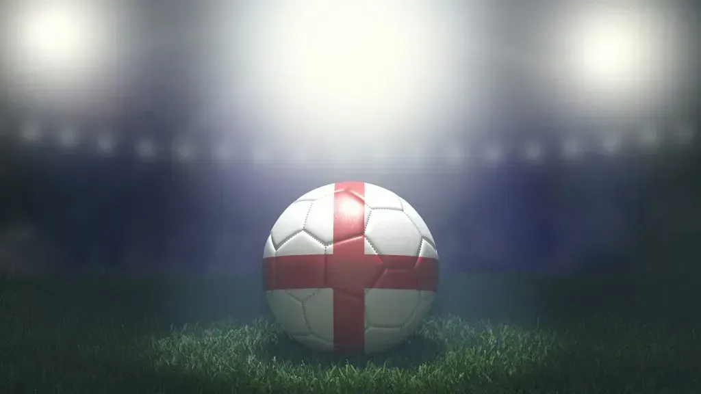 Bola de futebol com representação da bandeira da Inglaterra está sobre o gramado do campo
