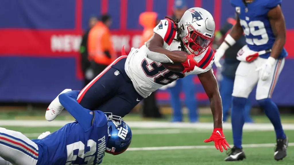 Rhamondre Stevenson #38 of the New England Patriots stretches over Jason Pinnock #27 of the New York Giants while scoring a rushing touchdown during the third quarter at MetLife Stadium on November 26, 2023 in East Rutherford, New Jersey.
