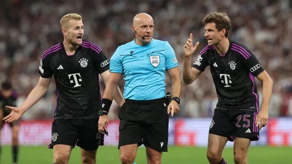 Referee Szymon Marciniak looks on with Matthijs de Ligt and Thomas Mueller of Bayern Munich during the UEFA Champions League semi-final second leg match between Real Madrid and FC Bayern München at Estadio Santiago Bernabeu on May 08, 2024 in Madrid, Spain.