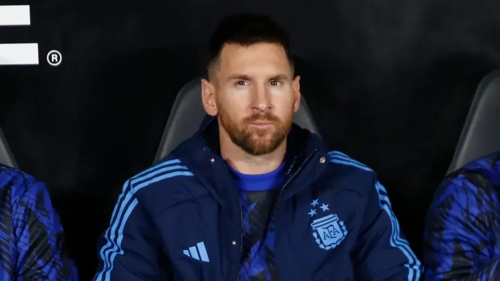 Lionel Messi of Argentina (C) sits in the bench with teammates Giovani Lo Celso (L) and Leandro Paredes (R) prior to the FIFA World Cup 2026 Qualifier match between Argentina and Paraguay at Estadio Más Monumental Antonio Vespucio Liberti on October 12, 2023 in Buenos Aires, Argentina.