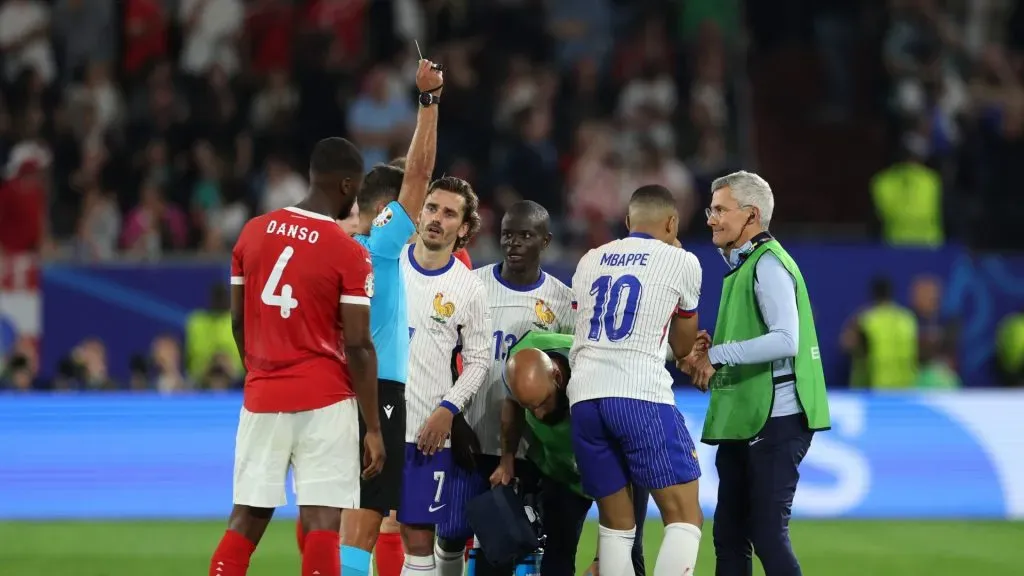 Kylian Mbappe of France is shown a yellow card by Referee Jesus Gil Manzano as he is helped up by medical staff following clashing heads with Kevin Danso of Austria.